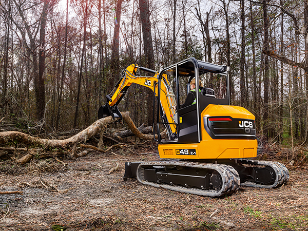 JCB compact excavator moving a large branch