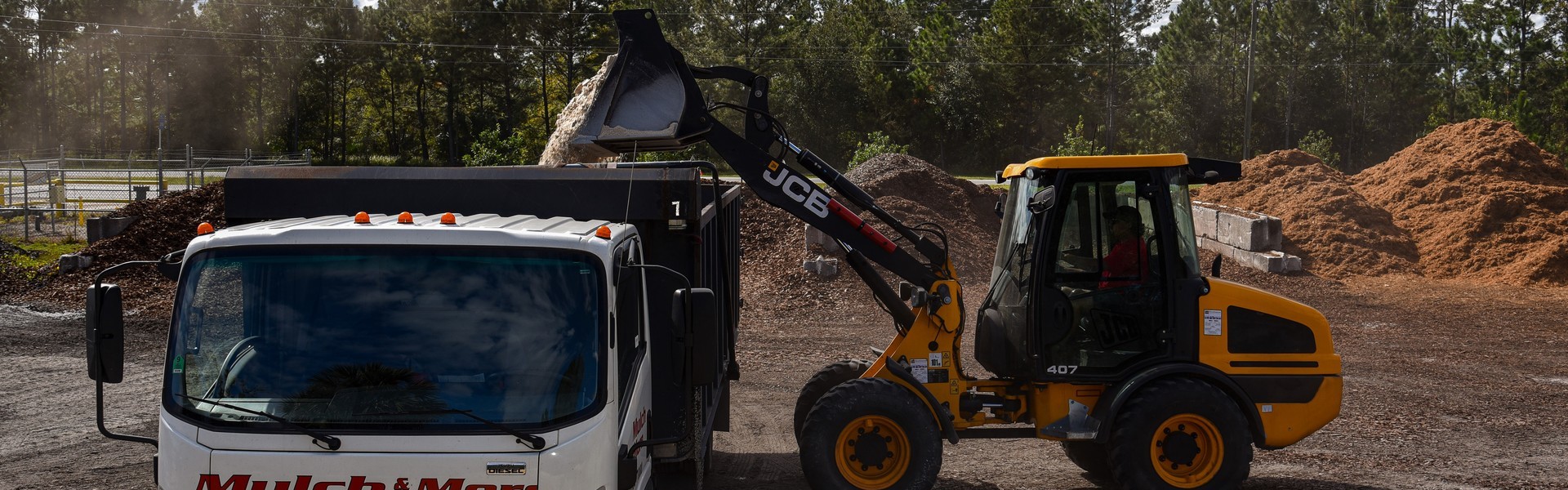 JCB wheel loader moving mulch into truck